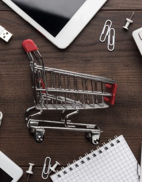 shopping online concept shopping online concept. small red trolley and gadgets on the table